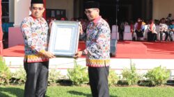 Pj Bupati Bolmut Sirajudin Lasena saat menyerahkan piagam penghargaan terkait penyelenggaraan KKS di Bolmut kepada Kadis Kesehatan Ali Dumbela