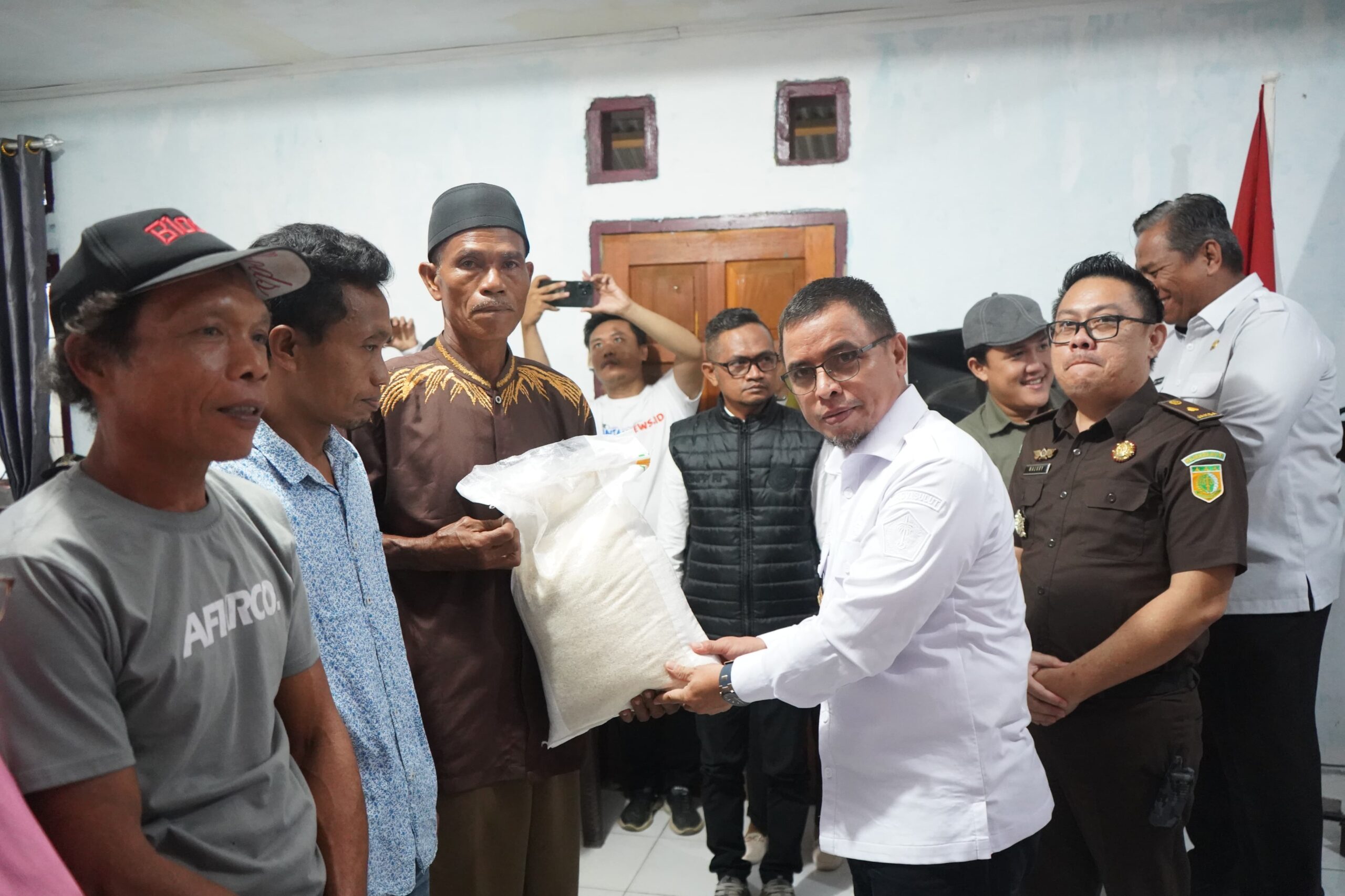 Pj Bupati Bolmut Sirajudin Lasena saat menyalurkan bantuan pangan ke warga
